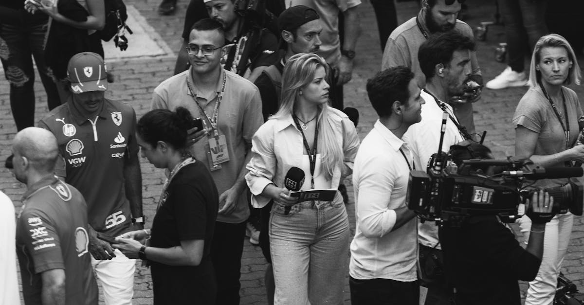 Black and white image of a bustling outdoor event with reporters and camera crews.