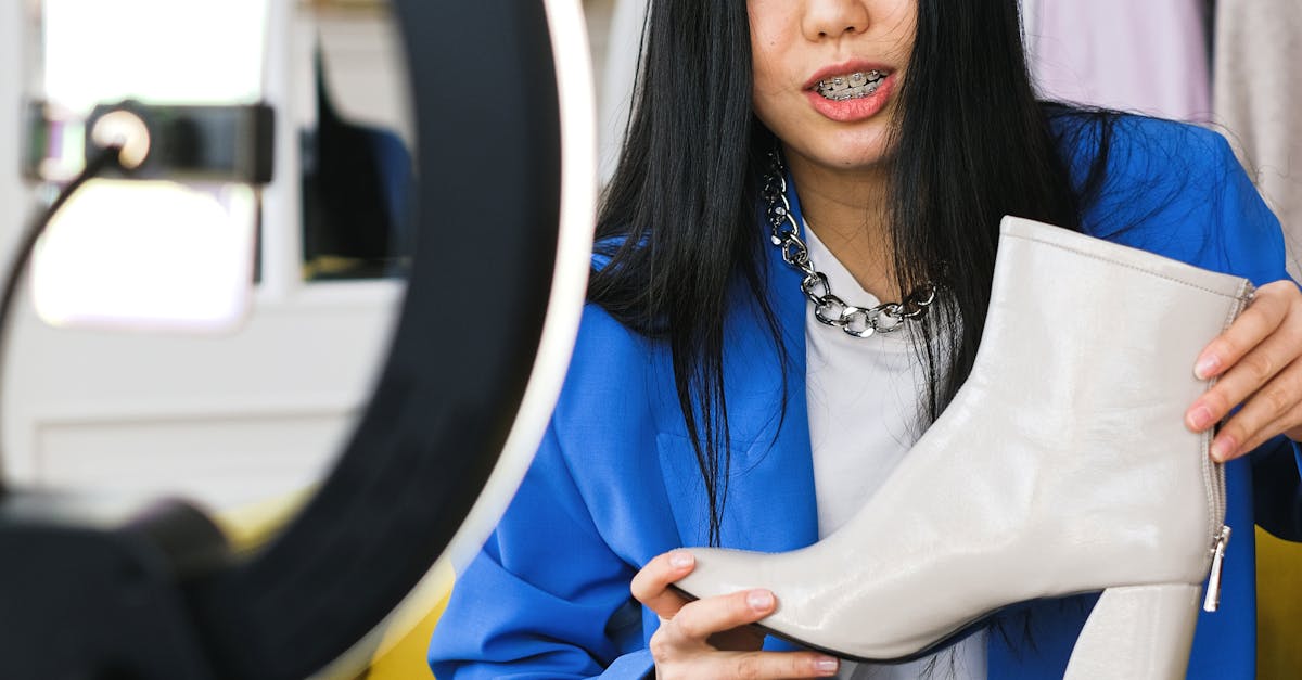 Young woman fashion vlogger recording a video about stylish white boots indoors.